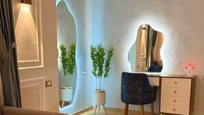 A modern living room with a sofa, a glass coffee table, a desk with a chair, and two potted plants. - Royal hotel tanta (Tanta)