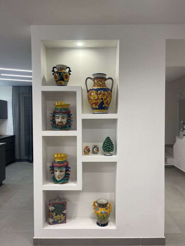 A white shelving unit displaying various ceramic vases and figurines.