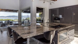 Una cucina moderna con una grande isola, elettrodomestici in acciaio inossidabile e vista sul mare.