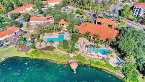 Luchtbeeld van een resort met een groot zwembad, meerdere gastvrijen en weelderige begroeiing rondom het terrein.