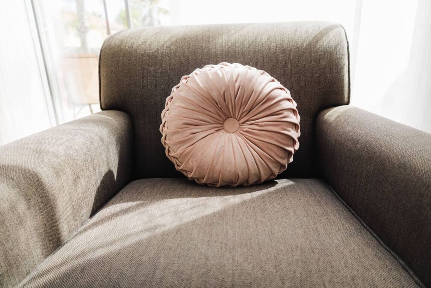 Un fauteuil marron avec un coussin rond à motifs en relief.