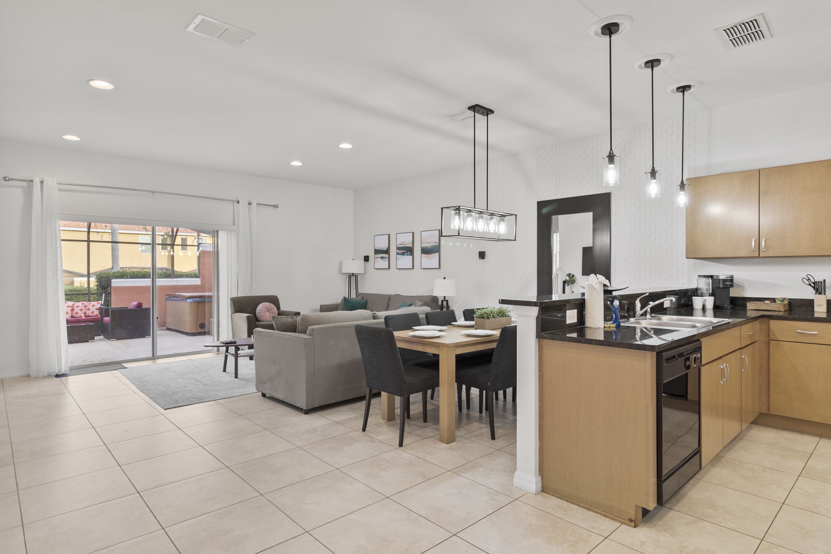 Cocina moderna con una isla central, comedor con sillas y sala de estar con sofá y una mesa de centro.