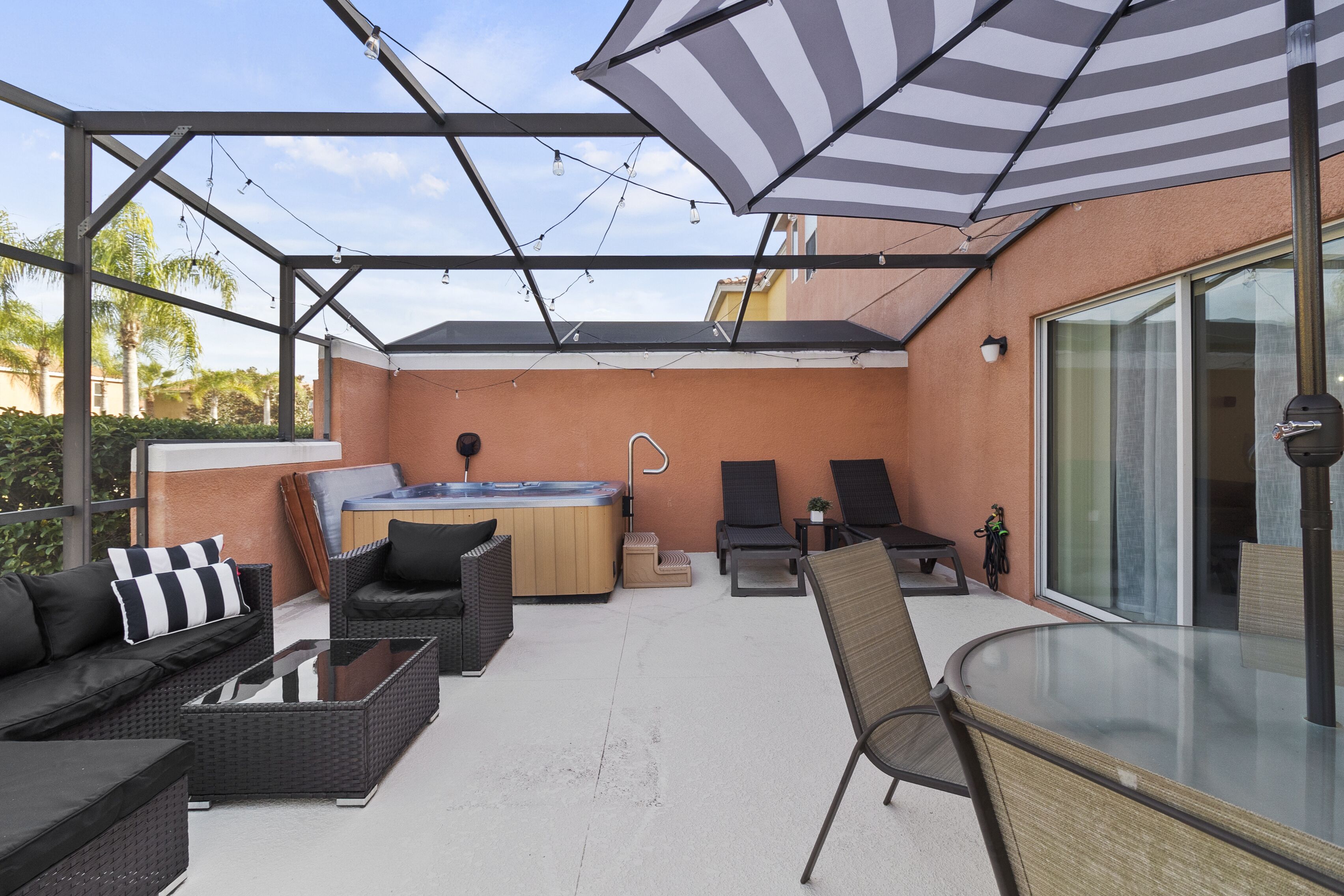 Un patio exterior con un jacuzzi, sillones de descanso y una mesa de vidrio.