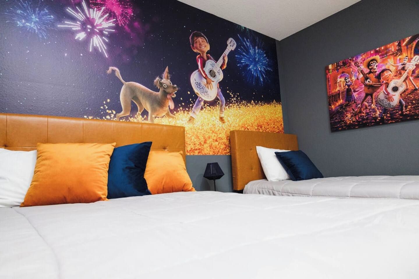 A hotel room with a bed, two pillows, a nightstand, and a wall mural.