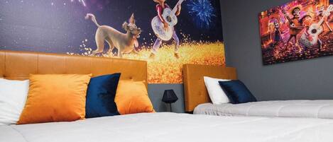 Habitación de hotel con cama, dos almohadas, una mesita de noche y un mural en la pared.