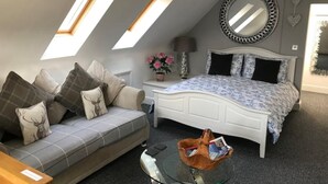 Una camera da letto con un letto, un divano, un tavolino in vetro e un lucernario.