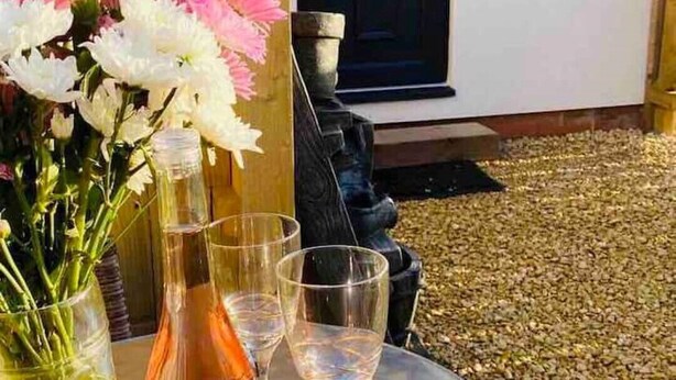Un tavolo rotondo con un vaso di vetro pieno di fiori e due bicchieri da vino.