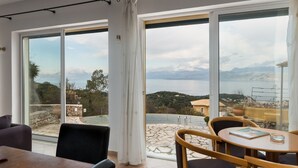 A modern room with large sliding glass doors leading to a terrace with a scenic view of the sea and mountains. - The Hillside Villas, Stunning Views & Private Pool (Corfu)