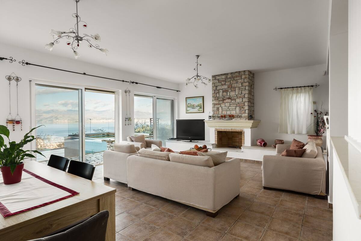 A spacious living area with a large sofa, a dining table, and a fireplace.
