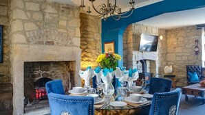 A dining room with a stone fireplace, blue walls, and a chandelier. - The Anchorage - sea views and beach on doorstep (Amble)