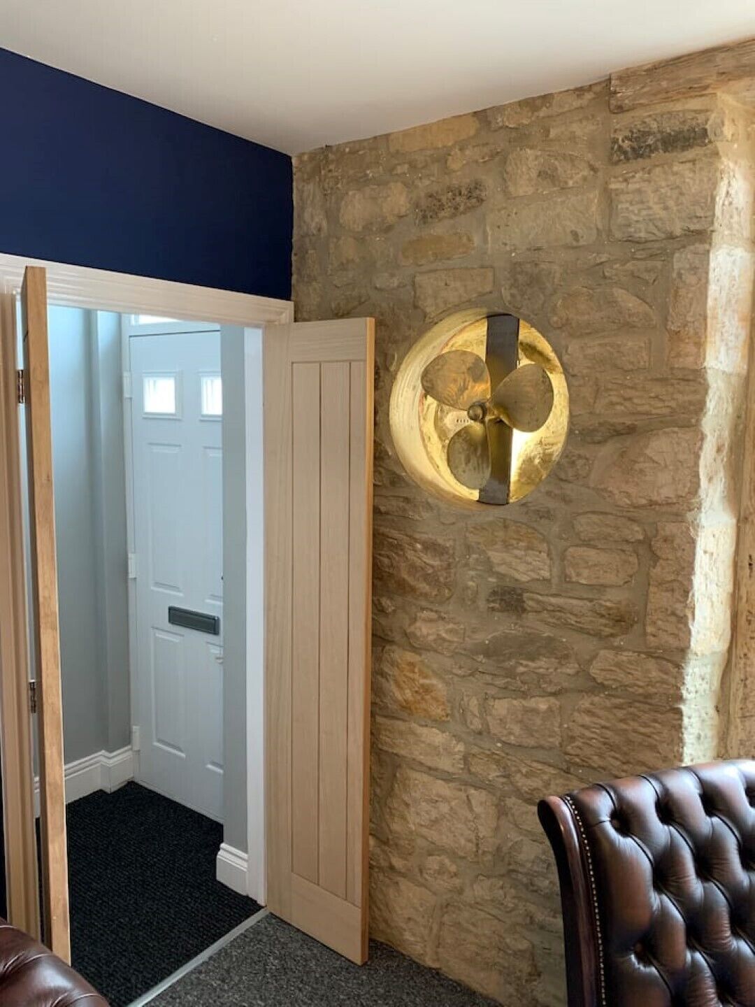 Quarto com parede de pedra, uma porta e um aplique na parede.