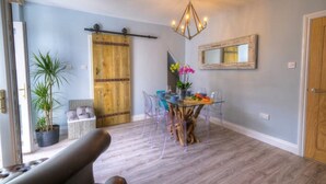 A dining area with a wooden door, a chandelier, and a dining table with chairs. - The Rockpool - Private HOT TUB + Sea Views (Amble)
