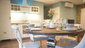 A modern kitchen with white cabinetry, a round dining table, and a stone accent wall.