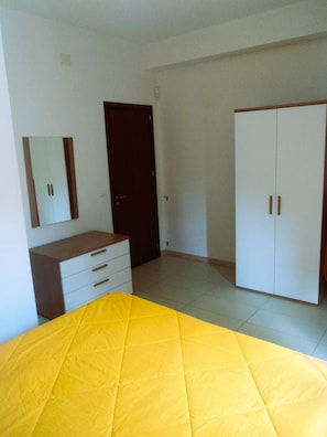 A bedroom with a bed, a dresser, a wardrobe, and a door.