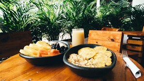 A wooden table with a bowl of fruit, a bowl of scrambled eggs, and a glass of milk. - Neos Hotel Cartagena (Cartagena)