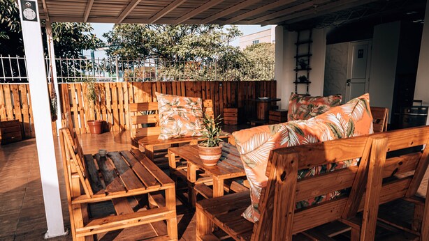 Un espacio al aire libre con mesas y bancos de madera, una planta en maceta y una cerca de madera.
