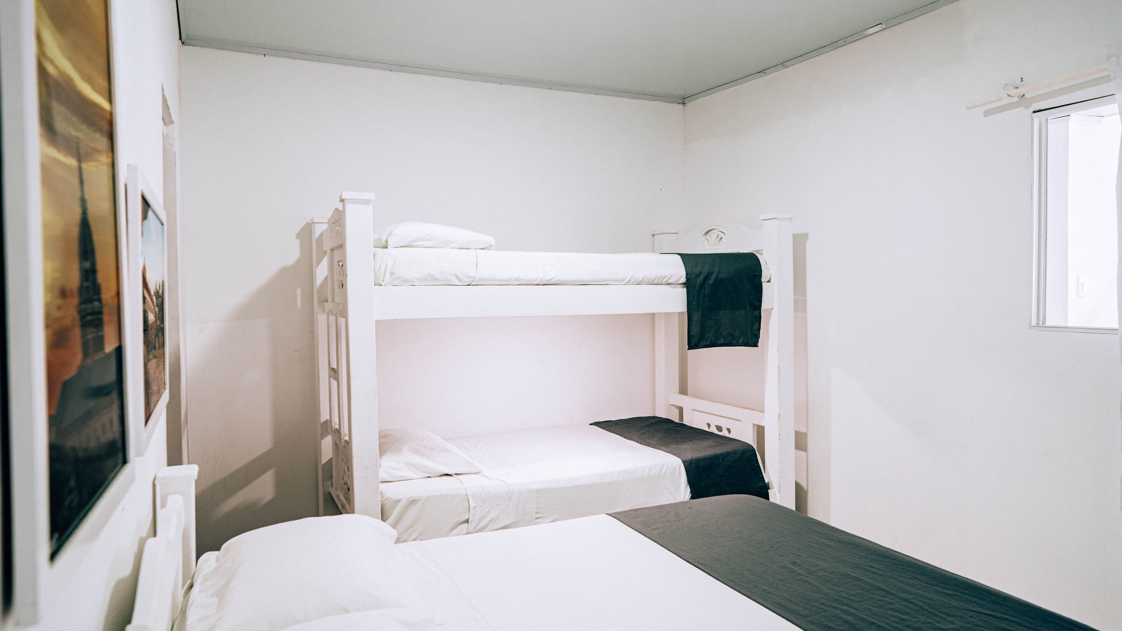 A bunk bed room with white bedding and a window.