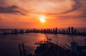 A city skyline at sunset with a large body of water in the foreground. - Neos Hotel Cartagena (Cartagena)