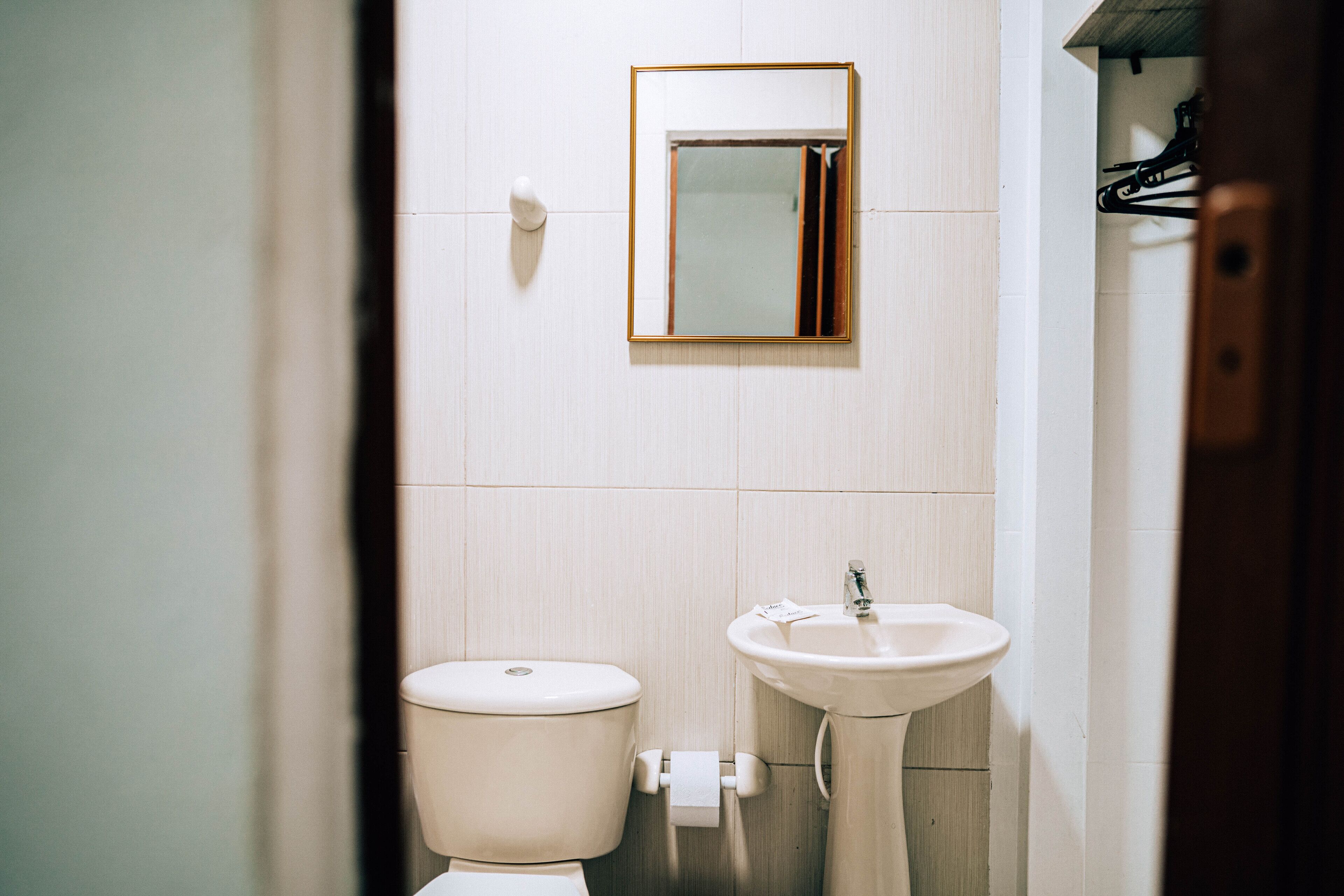 A bathroom with a toilet, sink, and mirror.