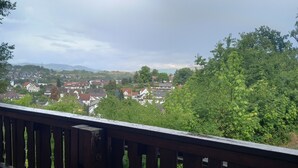 Une terrasse en bois offrant une vue sur la ville et la végétation environnante.