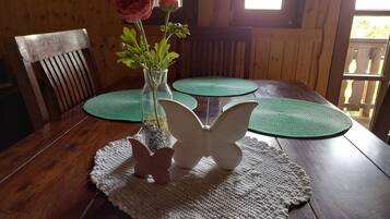Ein Holztisch mit einer Blumenvase, einem kerzenhalter in Schmetterlingsform und grünen Platzsets.