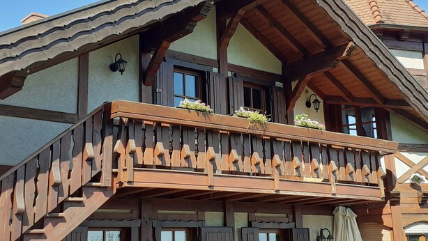 Un chalet traditionnel doté d’un balcon en bois, de lucarnes et d’un toit à forte pente.