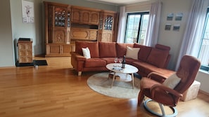 A living room with a brown leather sofa, a round coffee table, and a wooden cabinet with glass doors.