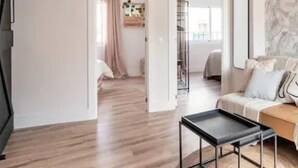 Un soggiorno moderno con parquet, un tavolino da caffè nero e un divano con cuscini.
