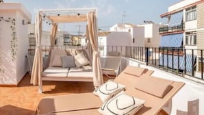 Una terrazza panoramica con un letto a baldacchino, poltrone relax e vista sulla città.