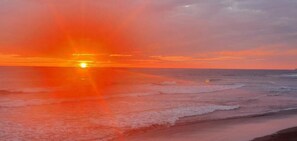 Un coucher de soleil sur l’océan, avec des vagues qui se rapprochent du rivage.