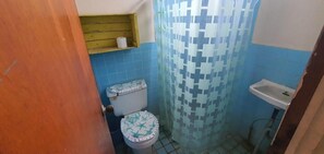 A small bathroom with a toilet, a sink, and a shower curtain. - Hostal Club Mochilero (La Libertad)