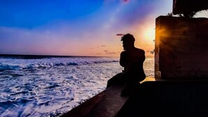 A silhouette of a person sitting by the ocean at sunset. - Hostal Club Mochilero (La Libertad)