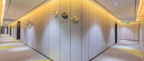 A hotel corridor with a curved wall, a reception desk, and a carpeted floor.