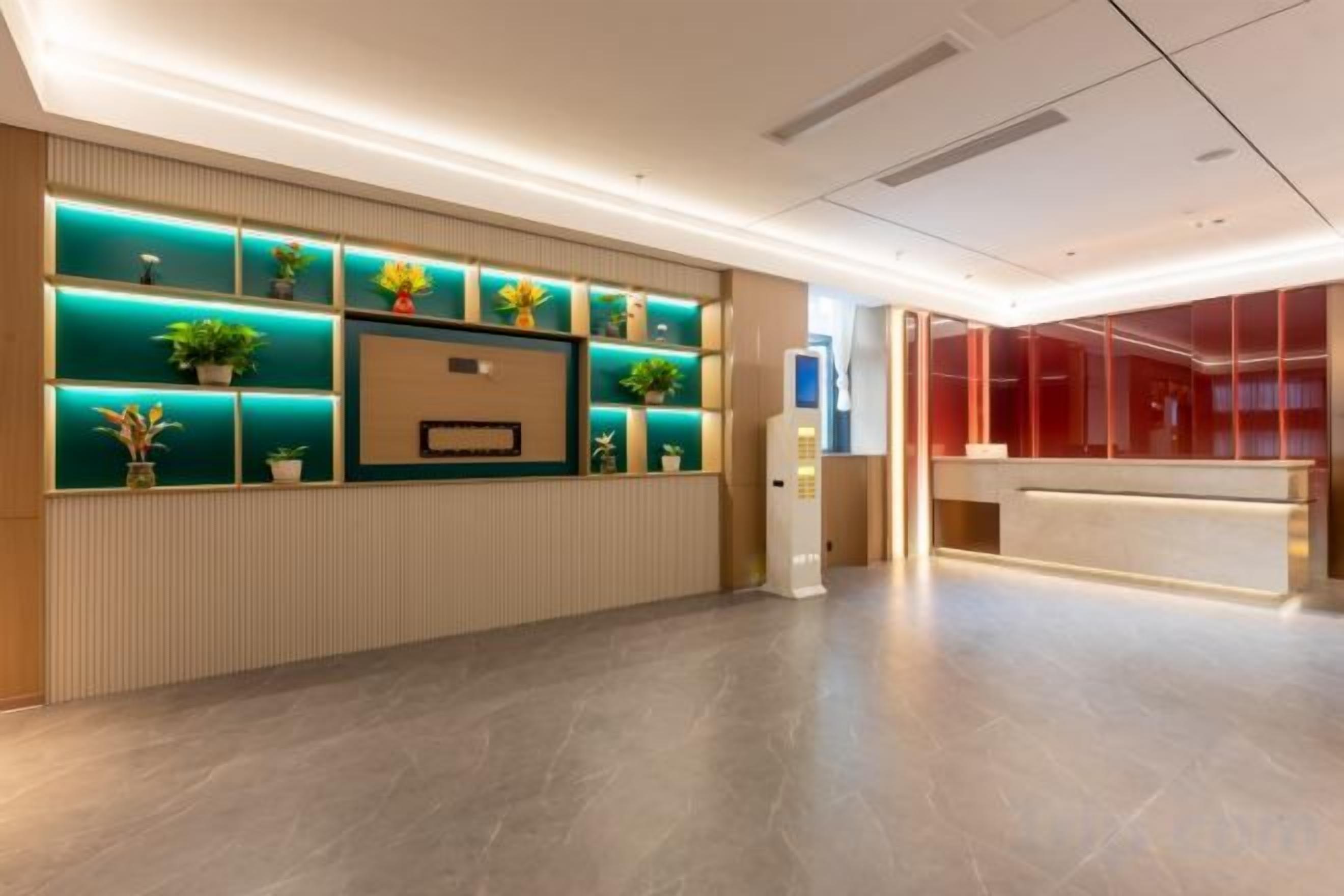 Un área de recepción con diseño moderno, que incluye un mostrador de recepción, una pantalla mural y varios estantes iluminados con plantas en macetas.