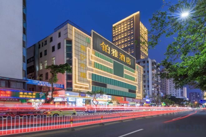 A multi-story hotel with illuminated signage, a modern facade, and a busy street in the foreground.