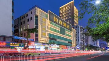 A multi-story hotel with illuminated signage, a modern facade, and a busy street in the foreground.
