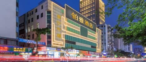 A multi-story hotel with illuminated signage, a modern facade, and a busy street in the foreground.