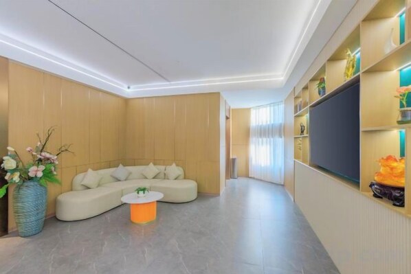 A modern living room with a sectional sofa, a coffee table, and a flat-screen TV mounted on the wall.