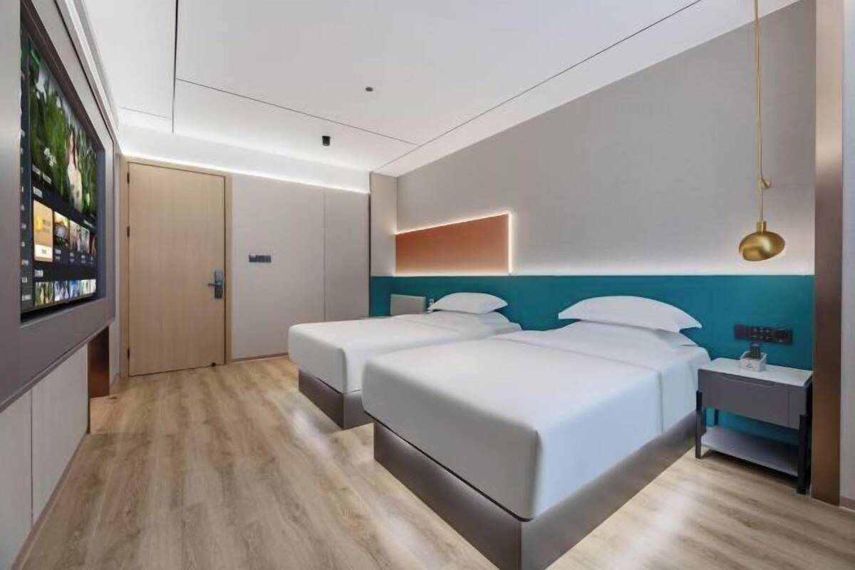 Une chambre d’hôtel moderne équipée de deux lits, d’une télévision, d’un bureau et d’une table de chevet.