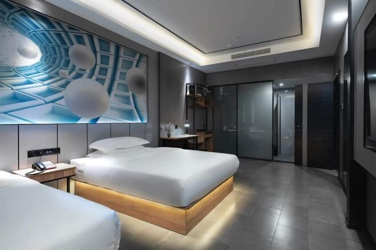 Une chambre d’hôtel moderne avec un grand lit, des tables de chevet, un bureau et un téléviseur fixé au mur.