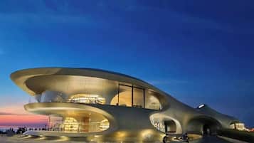A modern architectural building with a unique curved design, large windows, and a spacious outdoor area.