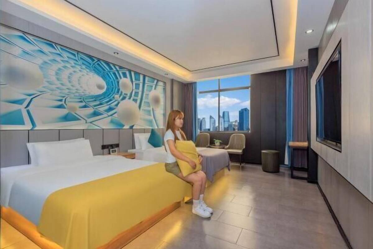 Une chambre d’hôtel moderne dotée d’un grand lit, d’un coin salon et offrant une vue sur la ville par la fenêtre.