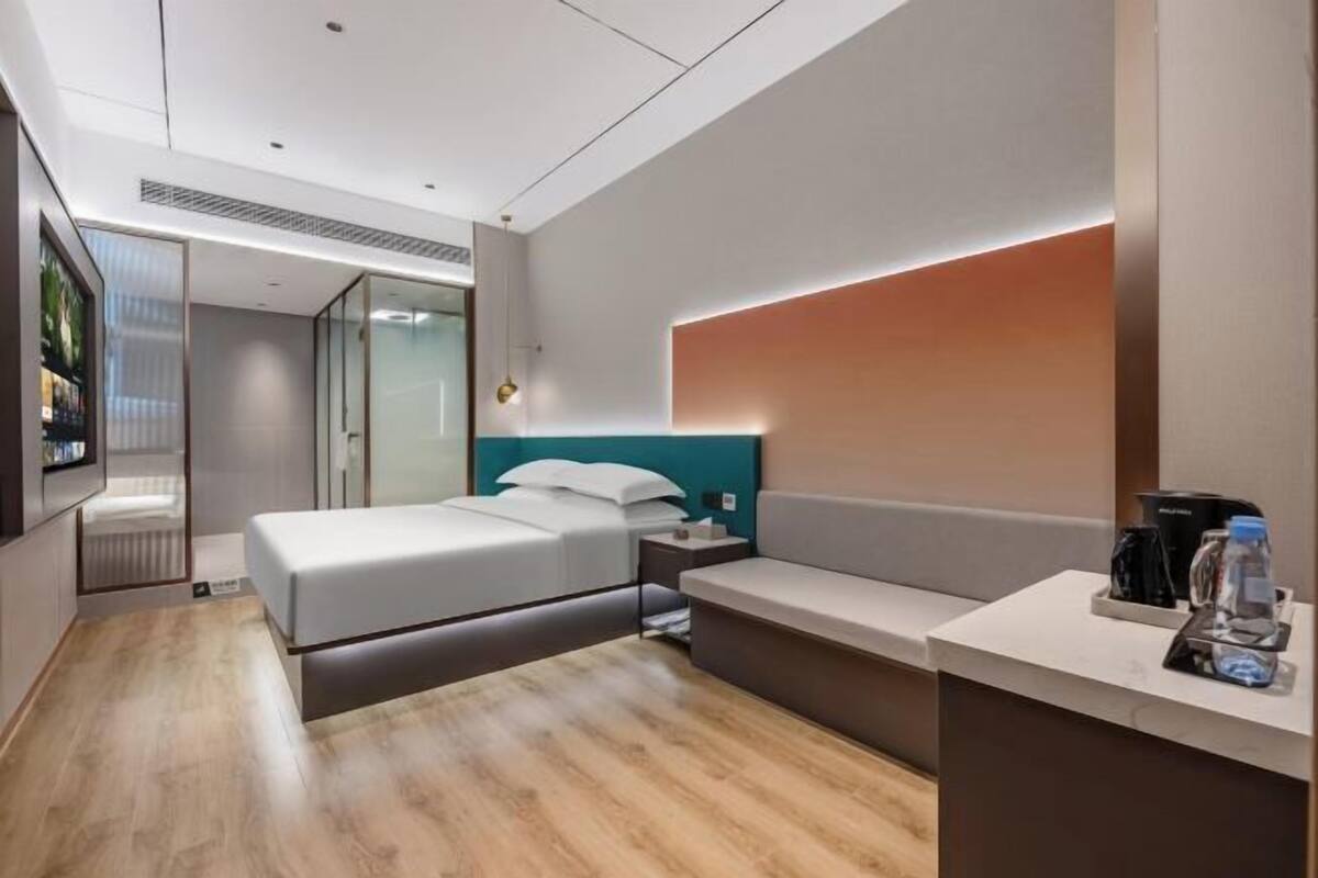 Une chambre d’hôtel moderne équipée d’un lit, d’une table de chevet et d’un petit bureau.