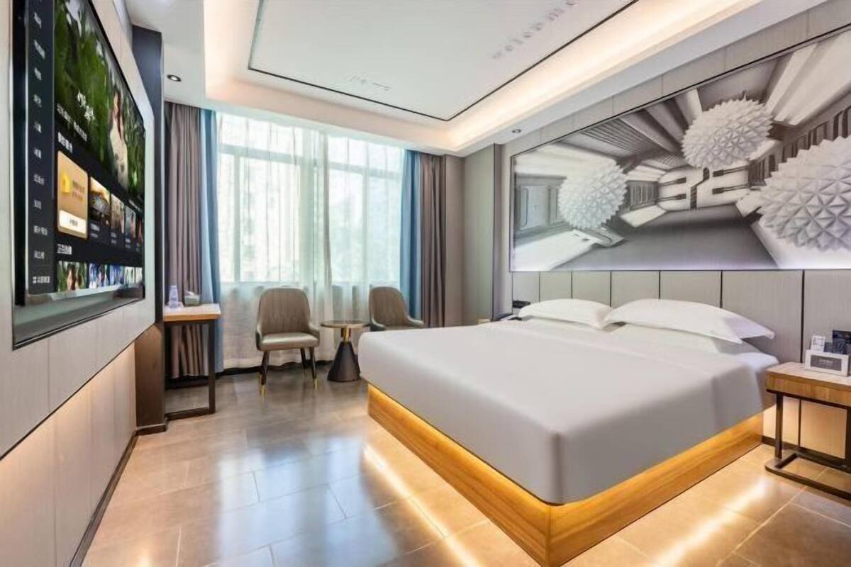 Une chambre d’hôtel moderne avec un grand lit, un bureau équipé d’un ordinateur et une grande fenêtre.