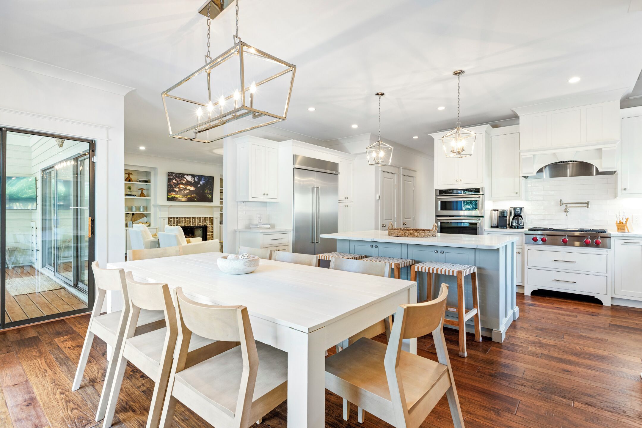 A modern kitchen with white cabinetry, stainless steel appliances, and a central island with stools.