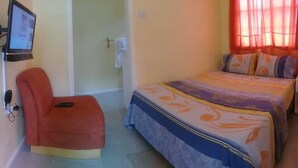 Ein Schlafzimmer mit einem Bett, einem Sessel, einem Nachttisch und einem Fernseher.