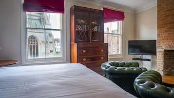 A bedroom with a large bed, a wooden cabinet, a leather sofa, and a television.