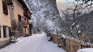 En snødekt gade med bygninger langs den ene side og et bjerg i baggrunden.
