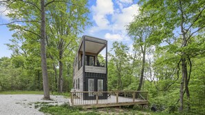 Une cabane moderne dotée d’une terrasse, entourée d’arbres.