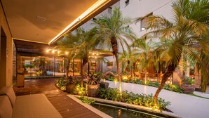 Un jardin intérieur moderne agrémenté d’un élément aquatique, d’un espace salon et de plantes en pot.